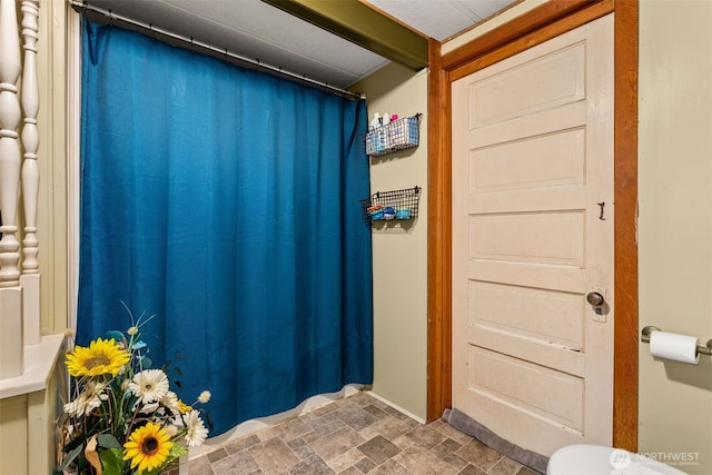 full bathroom featuring stone finish flooring and a shower with curtain