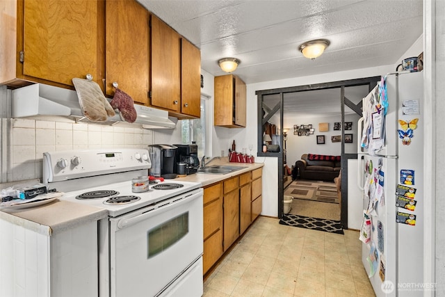 kitchen featuring brown cabinetry, white appliances, light countertops, and a sink