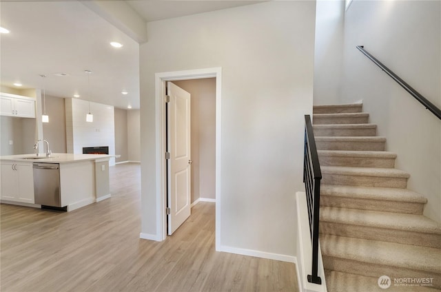 stairs with recessed lighting, baseboards, wood finished floors, and a fireplace