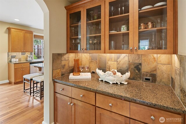 bar with baseboards, recessed lighting, backsplash, light wood-style floors, and arched walkways