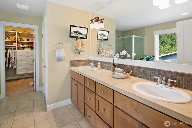 bathroom featuring a sink, decorative backsplash, tile patterned flooring, and a stall shower