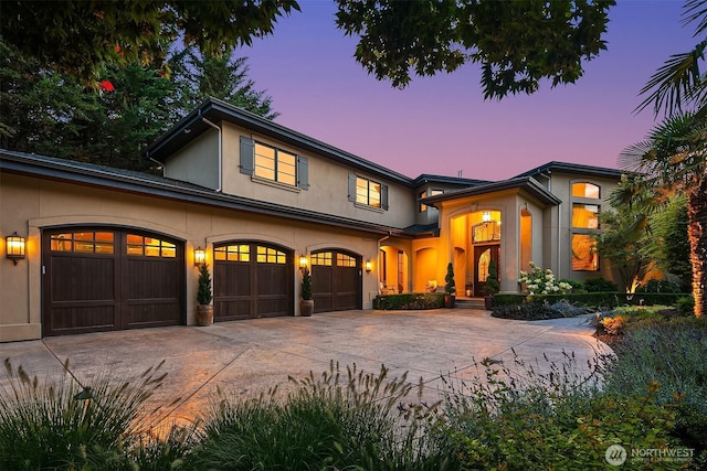 view of front of house with stucco siding, an attached garage, and concrete driveway