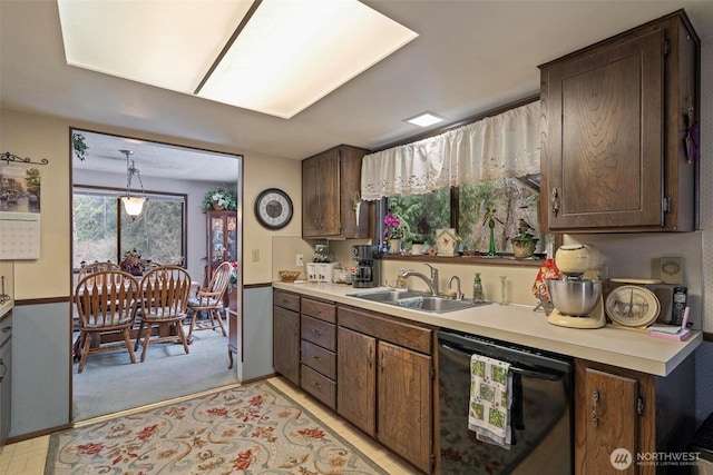 kitchen featuring dishwasher, light countertops, dark brown cabinetry, and a sink