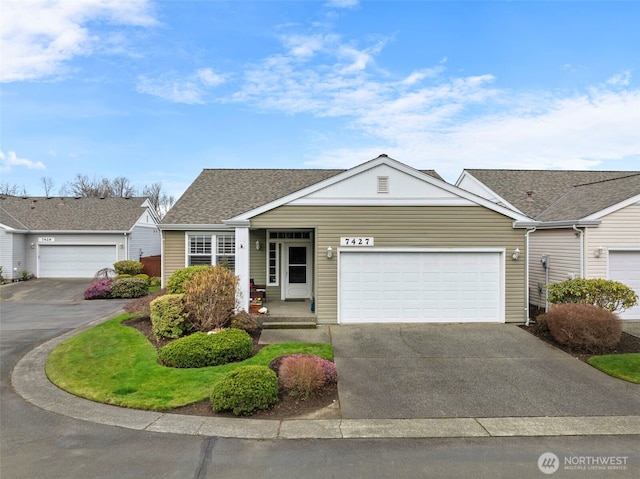 single story home with concrete driveway, an attached garage, and roof with shingles