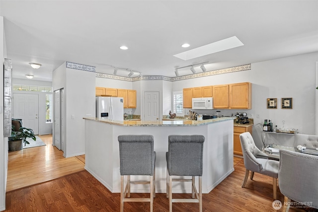 kitchen featuring a wealth of natural light, light brown cabinets, white appliances, and a skylight