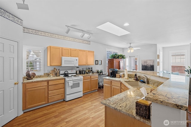 kitchen featuring a sink, white appliances, plenty of natural light, and a skylight