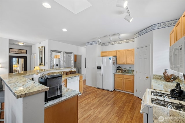 kitchen with recessed lighting, a large island with sink, a skylight, light wood-style floors, and white appliances