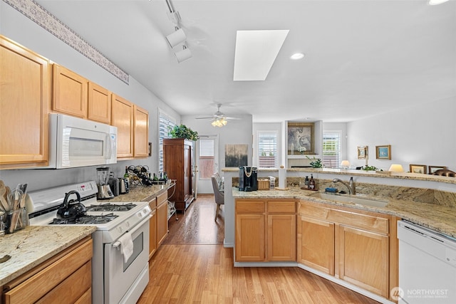 kitchen with light stone counters, white appliances, light wood-style floors, and a sink