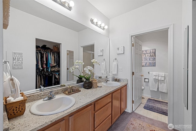 full bath with tile patterned flooring, double vanity, toilet, and a sink