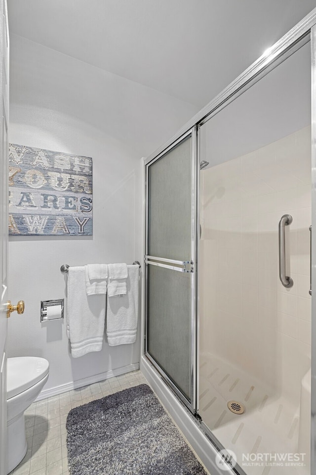 bathroom with tile patterned flooring, a shower stall, and toilet