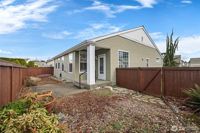 view of property exterior featuring a patio area, a fenced backyard, and a gate