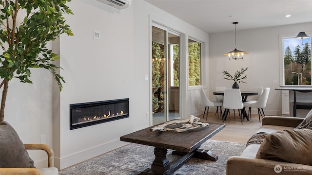 living area featuring a glass covered fireplace, recessed lighting, baseboards, and wood finished floors