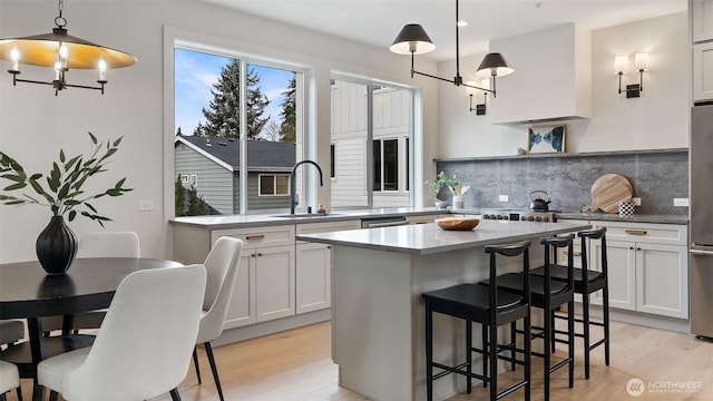 kitchen featuring a sink, light wood-style floors, backsplash, and a chandelier