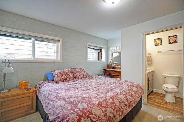 bedroom featuring connected bathroom, baseboards, and wood finished floors