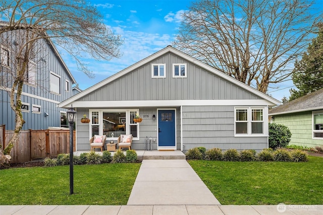 view of front of home with board and batten siding, a porch, a front yard, and fence