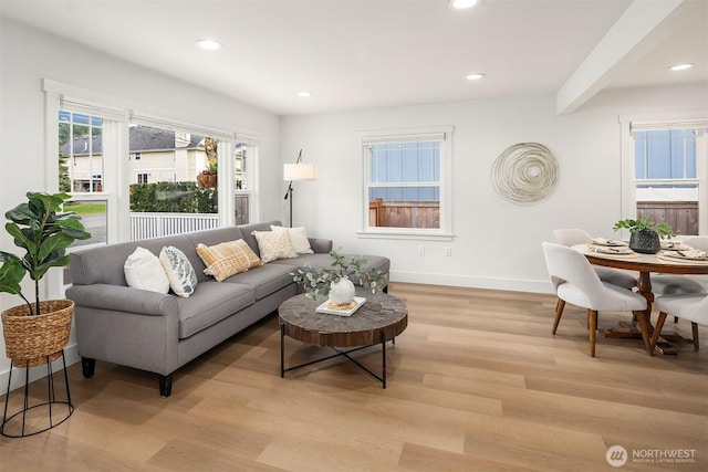 living room featuring recessed lighting, baseboards, beam ceiling, and light wood finished floors