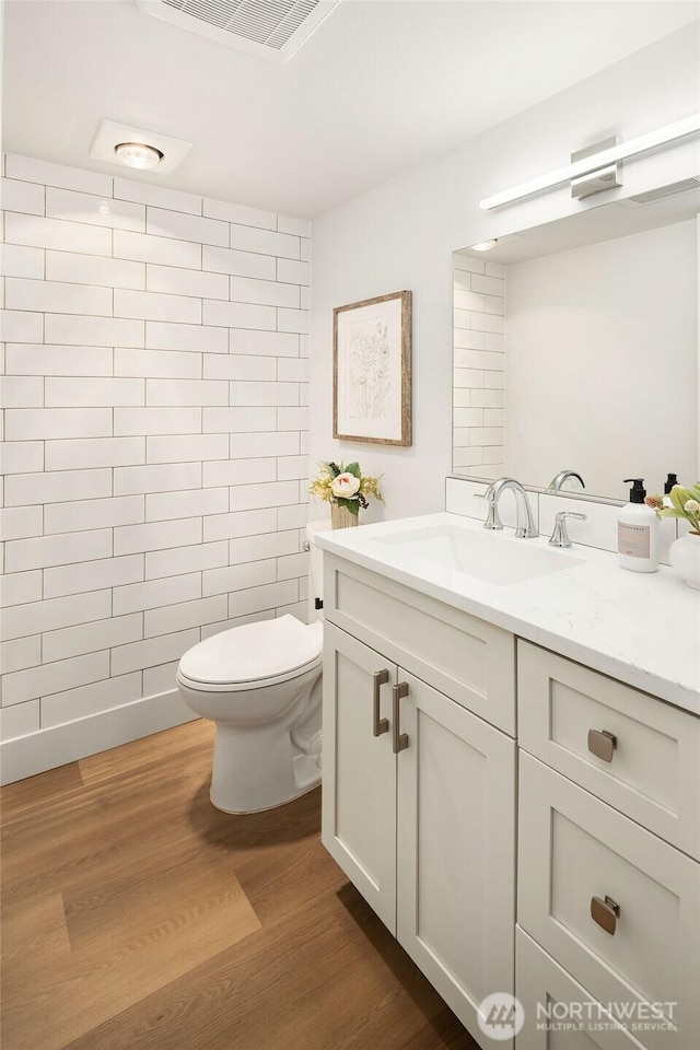 bathroom featuring vanity, toilet, wood finished floors, and visible vents