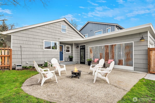 rear view of property featuring a patio, fence, a lawn, and an outdoor fire pit