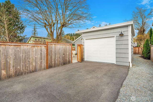 detached garage featuring aphalt driveway and fence