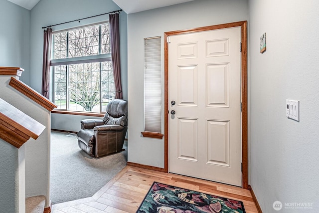 entrance foyer featuring baseboards, light wood-style floors, stairs, and vaulted ceiling