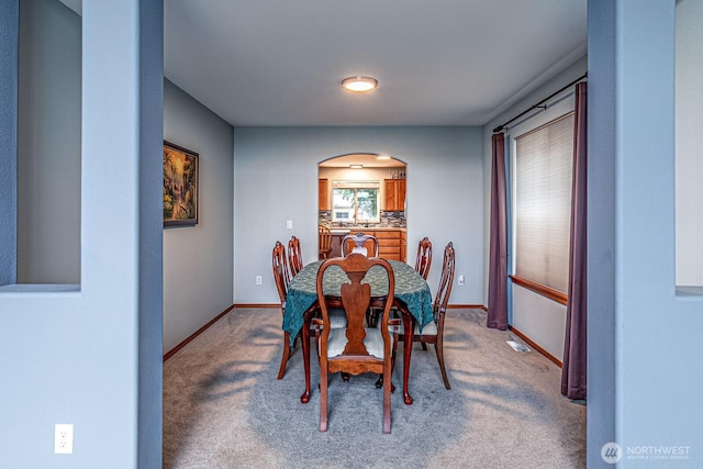 dining area featuring baseboards, arched walkways, and carpet floors