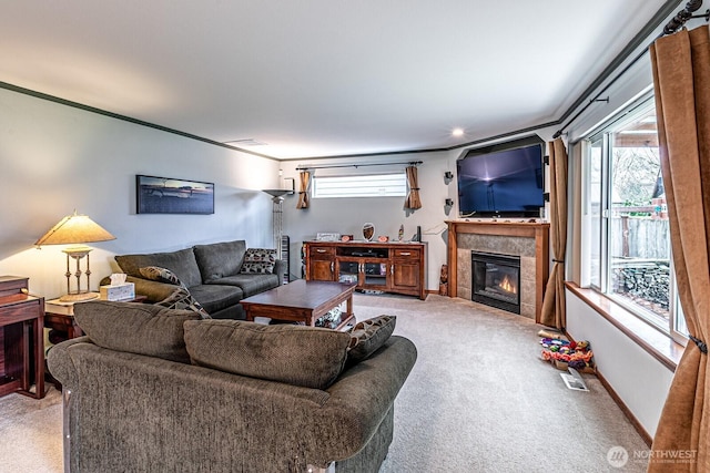 living area with baseboards, visible vents, a tile fireplace, crown molding, and carpet flooring