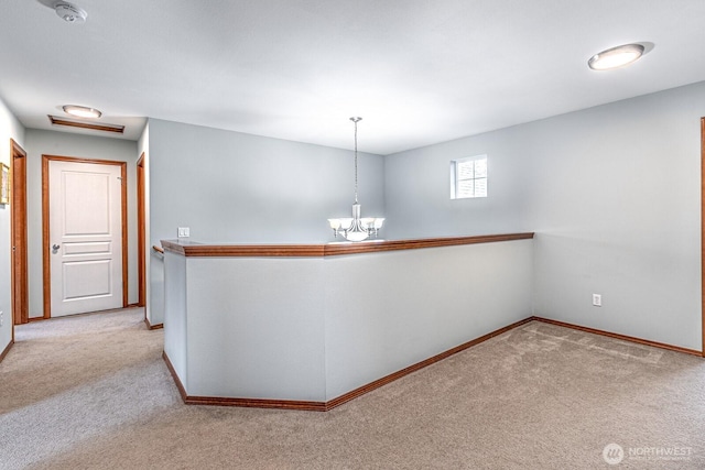 corridor featuring an inviting chandelier, carpet flooring, an upstairs landing, and baseboards