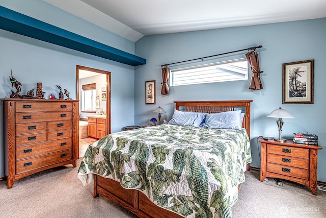 bedroom featuring connected bathroom, lofted ceiling, and light colored carpet