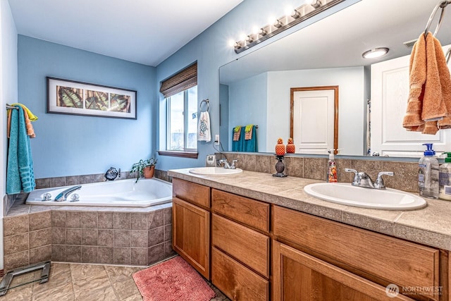 full bathroom featuring double vanity, a bath, and a sink