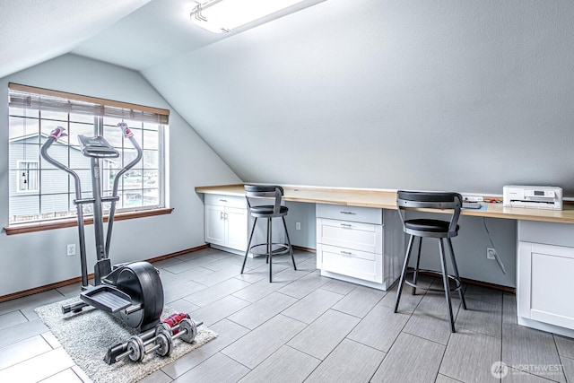 office area featuring baseboards, lofted ceiling, and built in study area