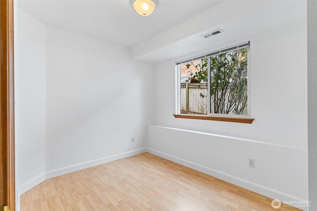 empty room featuring visible vents, baseboards, and wood finished floors