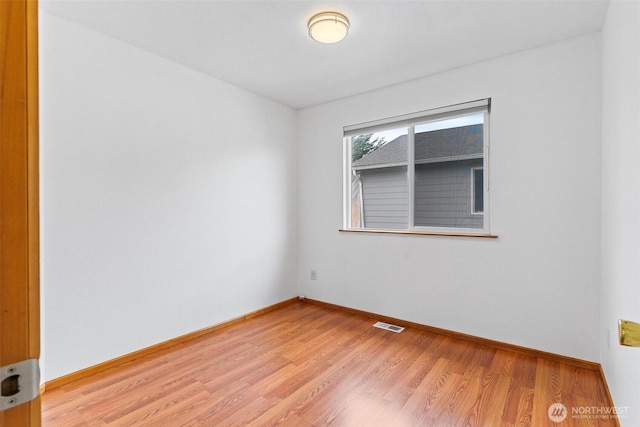 spare room featuring light wood-type flooring, baseboards, and visible vents