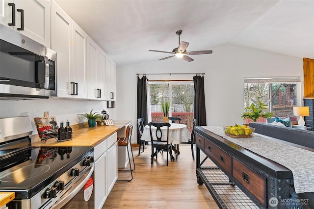 kitchen with appliances with stainless steel finishes, white cabinetry, lofted ceiling, and light wood-style floors