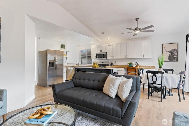 living room with light wood finished floors, baseboards, vaulted ceiling, recessed lighting, and a ceiling fan