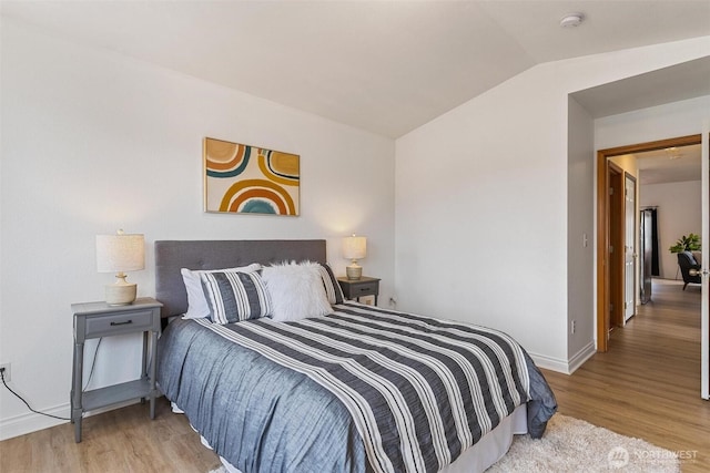 bedroom featuring wood finished floors, baseboards, and vaulted ceiling