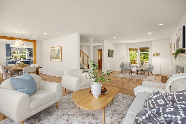 living area featuring recessed lighting, light wood-style flooring, baseboards, and stairway