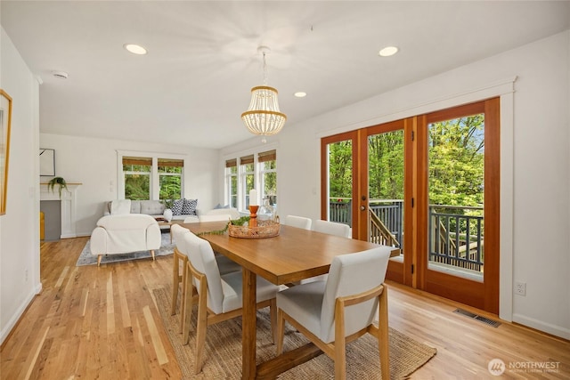 dining room featuring french doors, visible vents, baseboards, light wood finished floors, and a chandelier