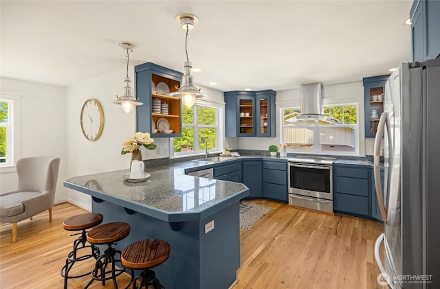 kitchen with appliances with stainless steel finishes, tile counters, a peninsula, island exhaust hood, and blue cabinets