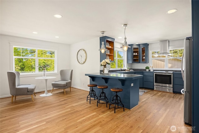 kitchen with a kitchen bar, island range hood, a sink, a peninsula, and stainless steel appliances