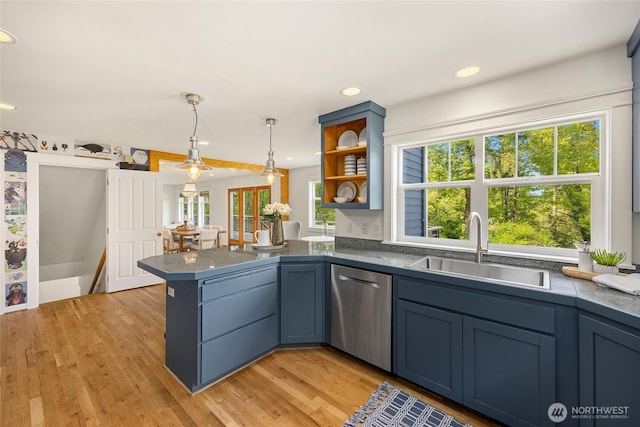 kitchen with pendant lighting, stainless steel dishwasher, a sink, a peninsula, and light wood-style floors