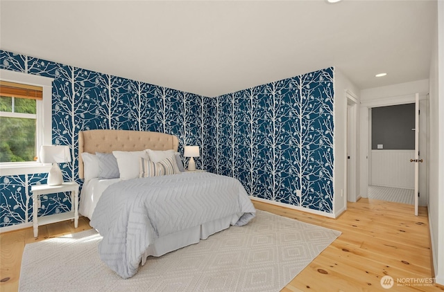 bedroom with recessed lighting, an accent wall, wood finished floors, and wallpapered walls
