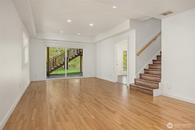 unfurnished living room with stairs, visible vents, and light wood-style flooring