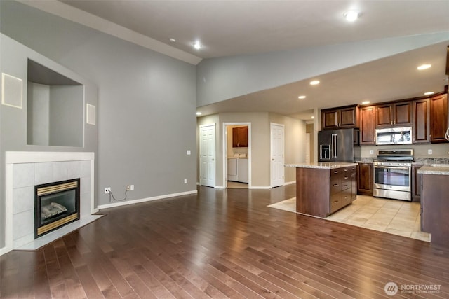 kitchen featuring light wood-style flooring, a kitchen island, open floor plan, stainless steel appliances, and vaulted ceiling