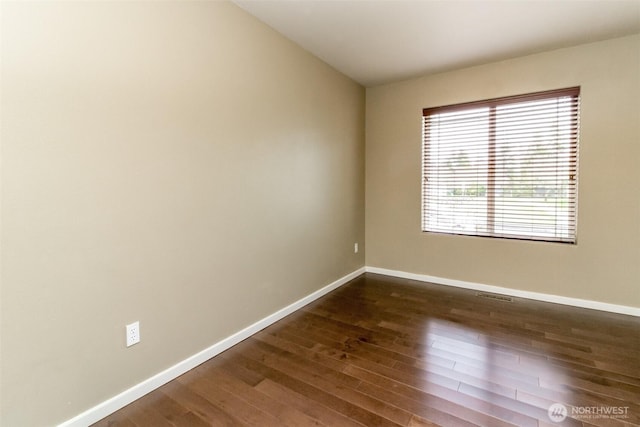 spare room with visible vents, baseboards, and dark wood-style flooring