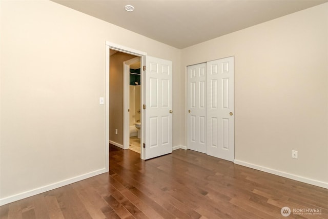 unfurnished bedroom featuring a closet, baseboards, and dark wood-style floors