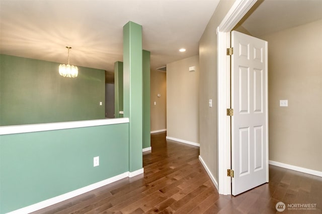 empty room featuring an inviting chandelier, recessed lighting, wood finished floors, and baseboards