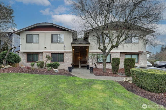 split level home with a front yard, brick siding, and stucco siding