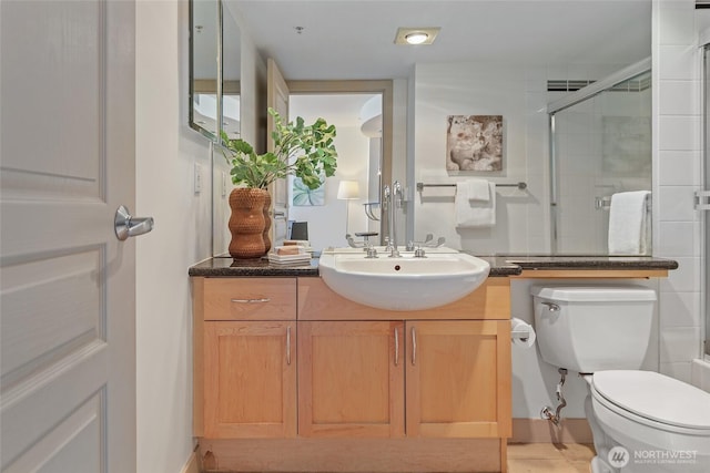 full bath featuring a shower with door, toilet, and vanity