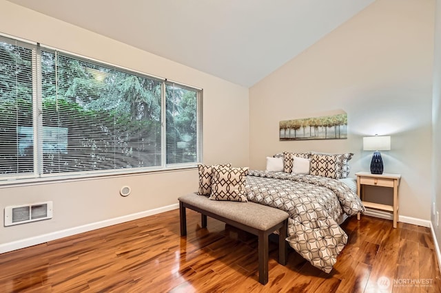 bedroom featuring visible vents, baseboards, lofted ceiling, and wood finished floors