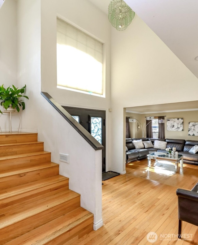 stairs featuring a towering ceiling and wood-type flooring